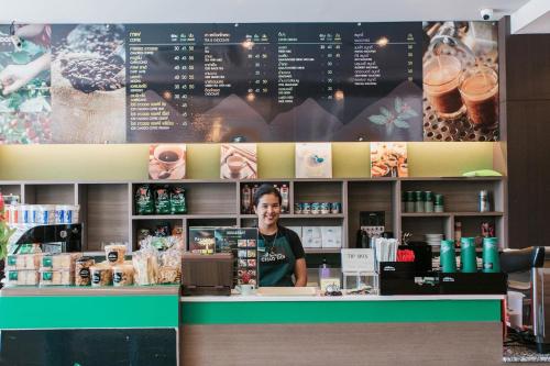 a man standing behind the counter of a coffee shop at The Centris Hotel Phatthalung in Phatthalung