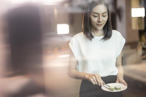 a woman is holding a plate of food at The Centris Hotel Phatthalung in Phatthalung
