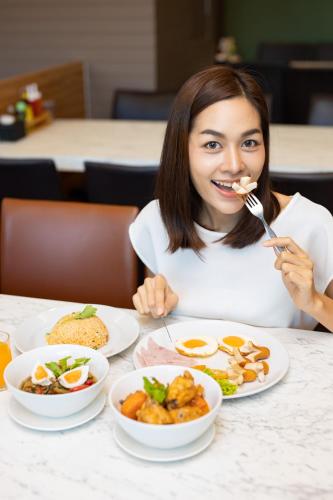 a woman sitting at a table with plates of food at The Centris Hotel Phatthalung in Phatthalung