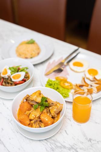 a white table topped with plates of food and drinks at The Centris Hotel Phatthalung in Phatthalung