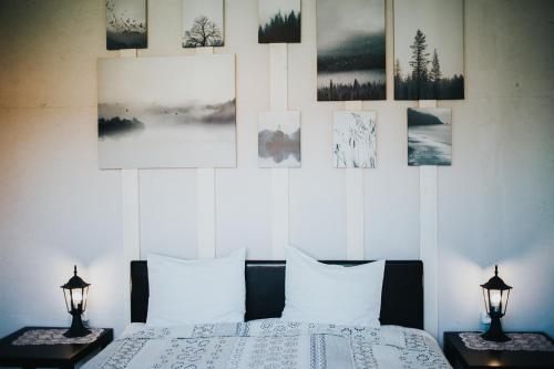 a bedroom with a bed and some pictures on the wall at Guest House Baltās Dūjas in Saulkrasti