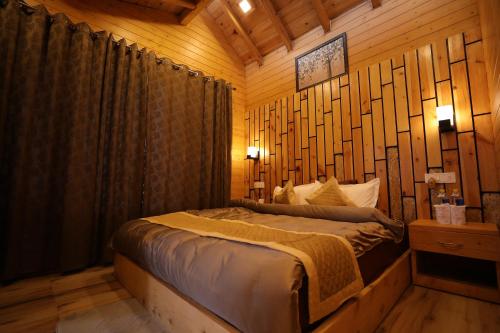 a bedroom with a bed in a room with wooden walls at Rooftop Cottages & Restaurant, Pangot in Nainital