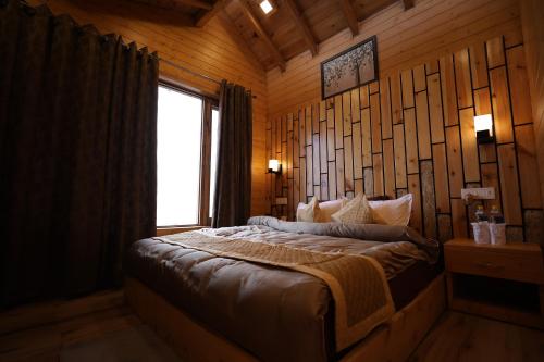 a bedroom with a bed in a room with a window at Rooftop Cottages & Restaurant, Pangot in Nainital