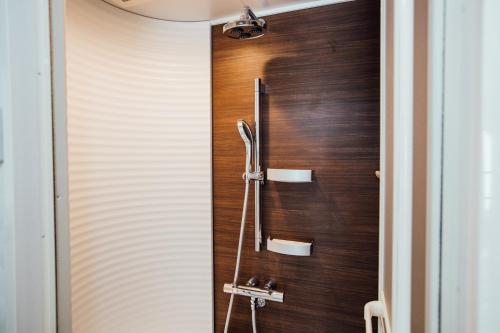 La salle de bains est pourvue d'une douche et d'un mur en bois. dans l'établissement 横浜元町, à Yokohama