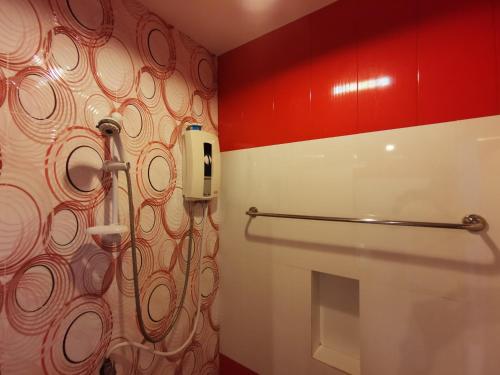 a bathroom with a toilet with a phone on the wall at Happy Field Resort in Cha Am
