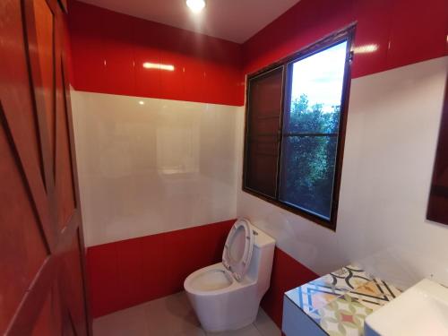 a bathroom with a toilet and a window at Happy Field Resort in Cha Am