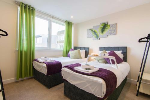 two beds in a room with green curtains at SUBLIME STAYS - Derby City Centre Apartments in Derby