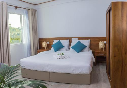 a bedroom with a large white bed with blue pillows at Nihaali Maldives in Kudarikilu
