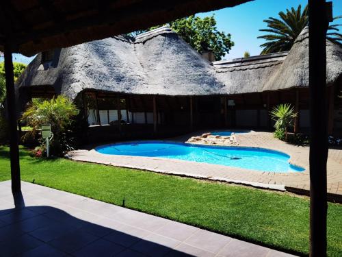 athatched house with a swimming pool in the yard at Heimat Guesthouse in Welkom