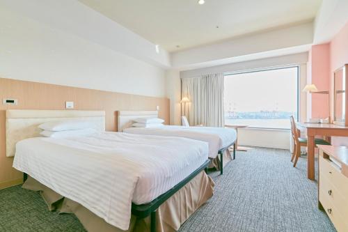 ein Hotelzimmer mit 2 Betten und einem großen Fenster in der Unterkunft Hotel Seagull Tenpozan Osaka in Osaka