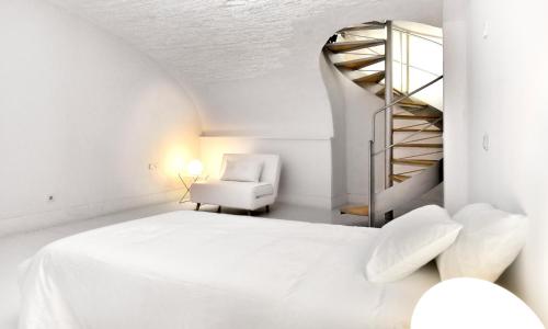 a bedroom with a white bed and a white chair at SA CASETA Sant Antoni 3 casa con encanto in Cadaqués