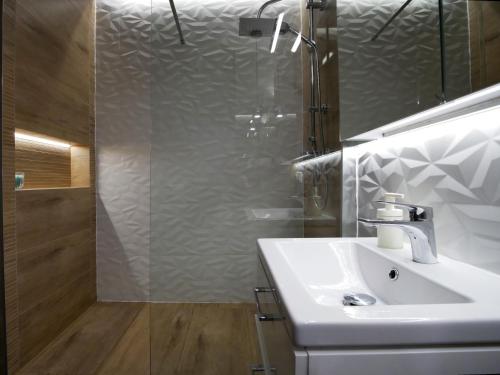 uma casa de banho com um lavatório branco e um chuveiro em 4UApart-Apartment studio Mohito em Świnoujście
