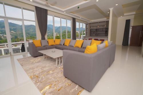 a living room with a gray couch and yellow pillows at Marseillia Hills in Puncak