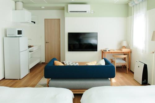 a living room with a blue couch and a kitchen at Hotel Potmum Sapporo in Sapporo