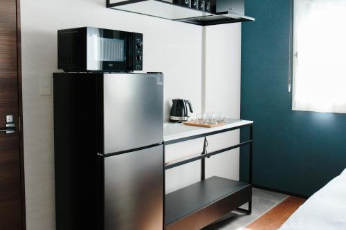 a small kitchen with a refrigerator with a microwave at Hotel Potmum Sapporo in Sapporo
