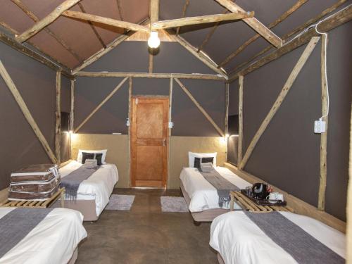 a room with three beds and a wooden door at Lapa Lange Game Lodge in Mariental