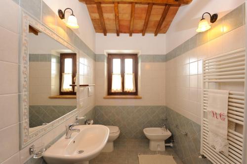 ein Badezimmer mit einem Waschbecken, einem WC und einem Spiegel in der Unterkunft Agriturismo L'Antica Fattoria in Bolsena