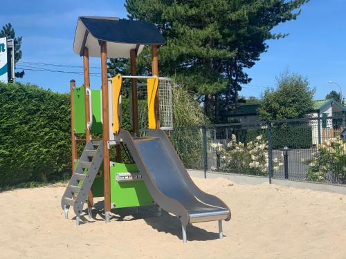 a playground with a slide in the sand at Camping Pomme de Pin in Stella-Plage