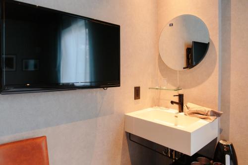 a bathroom with a sink and a tv on the wall at Hotel Potmum Sapporo in Sapporo