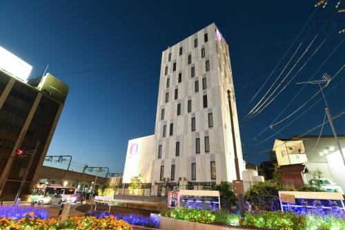 a tall white building in a city at night at Hotel Wisteria NARA in Nara