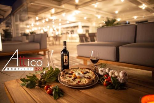 a table with a pizza and a bottle of wine at Hotel Monte Sarago in Ostuni