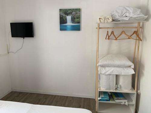 Habitación con cama y estante con TV. en Hôtel le petit randonneur, en Cilaos