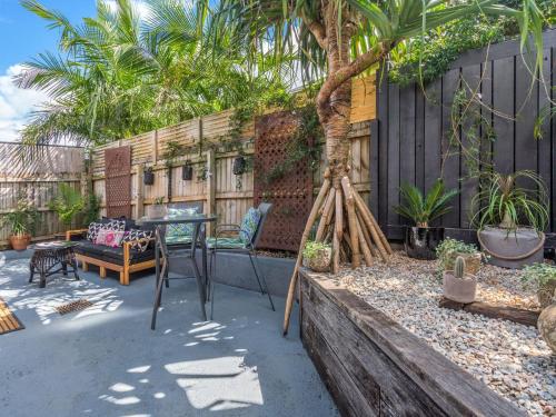 a patio with a table and a tree and a fence at Black Beauty Studio in Bangalow