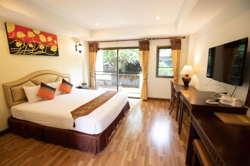 a bedroom with a bed and a desk and a television at Luckswan Resort Chiang Rai - SHA Extra Plus in Chiang Rai