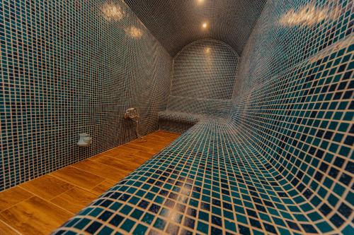 a bathroom with blue tiles on the wall and a shower at Seven Springs Hotel in Banya