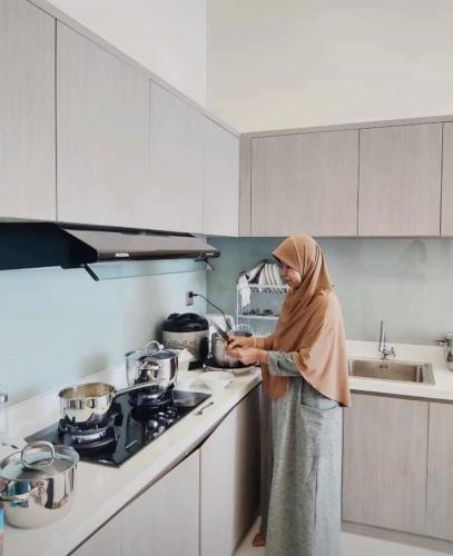 a woman standing in a kitchen preparing food at Marseillia Hills in Puncak