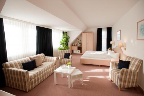 a living room with a couch and a bed at Hotel Friesenhof in Norderstedt