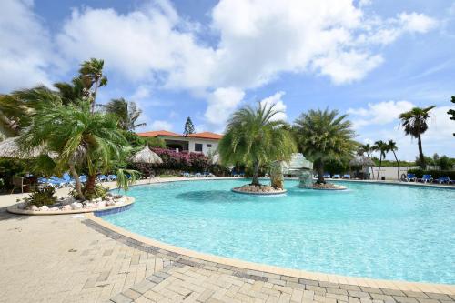 a swimming pool with palm trees in a resort at Seru Coral Apartment in Willemstad