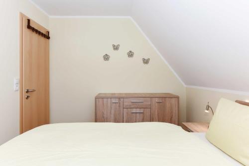 a bedroom with a white bed and a wooden cabinet at Ferienwohnung Teezeit in Neuharlingersiel