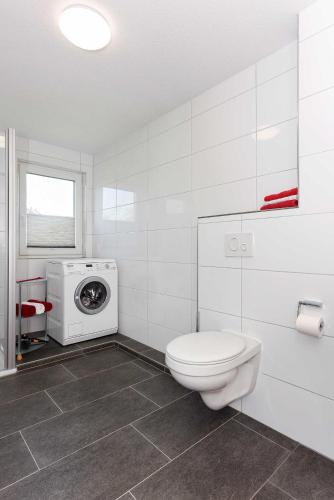 a bathroom with a toilet and a washing machine at Ferienwohnung Teezeit in Neuharlingersiel