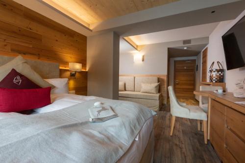a hotel room with a large bed and a desk at Mont Chalet Nevada - Hotel & Spa in Livigno