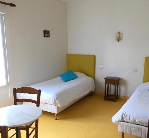 una stanza con due letti, un tavolo e delle sedie di La Ferme de la Maugerie a Thoury