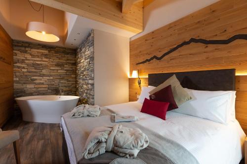 a bedroom with a large bed with a bath tub at Mont Chalet Nevada - Hotel & Spa in Livigno