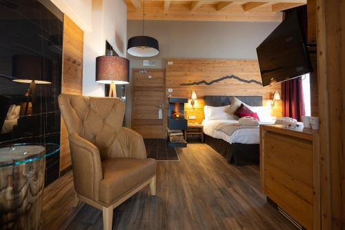 a bedroom with a bed and a chair at Mont Chalet Nevada - Hotel & Spa in Livigno