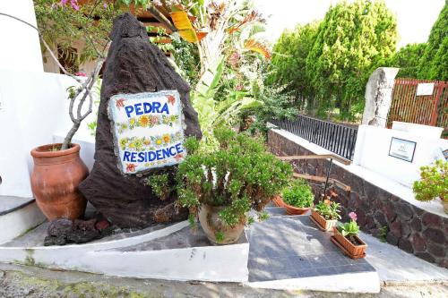 a sign in the shape of a rock with potted plants at Pedra Residence in Stromboli