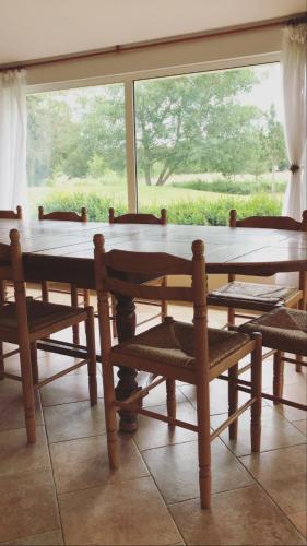 - une table et des chaises en bois dans une chambre avec fenêtre dans l'établissement La Ferme de la Maugerie, à Thoury