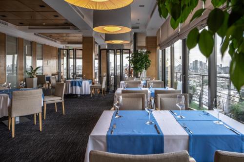 um restaurante com mesas e cadeiras azuis e janelas em CITYHOTEL em Kiev