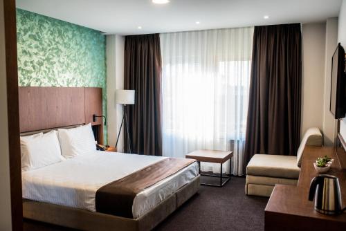 a hotel room with a large bed and a chair at Hotel Bograd - Apartments & Lounge Station in Struga