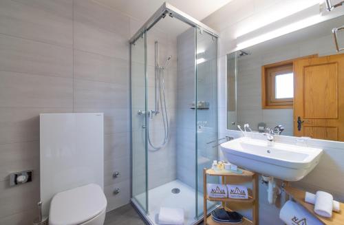 ein Bad mit einer Glasdusche und einem Waschbecken in der Unterkunft VIU Hotel Villars in Villars-sur-Ollon
