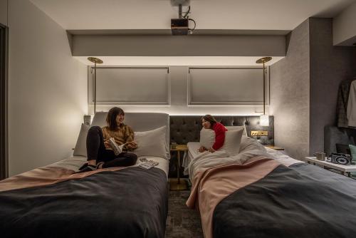 zwei Frauen auf Betten in einem Hotelzimmer in der Unterkunft slash kawasaki in Kawasaki