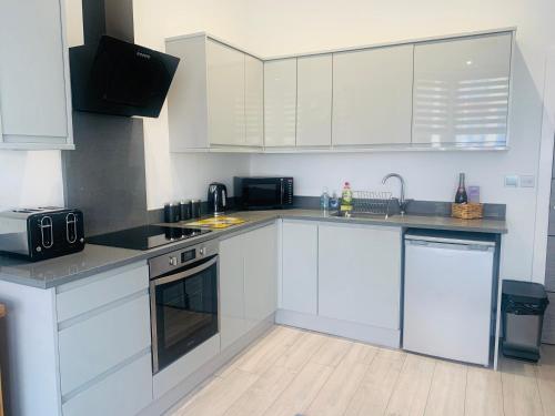a kitchen with white cabinets and a stove top oven at Sandleigh Apartment in Scarborough