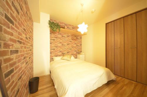 een slaapkamer met een bed en een bakstenen muur bij River Side Namba 400 in Osaka