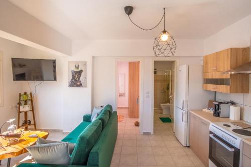 a living room with a green couch and a kitchen at Remvi GUEST HOUSE in Pramanta