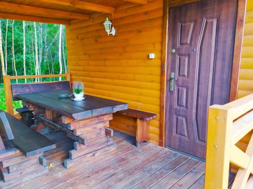 une véranda en bois avec une table en bois et une porte dans l'établissement Domek letniskowy Szramowo, à Zbiczno