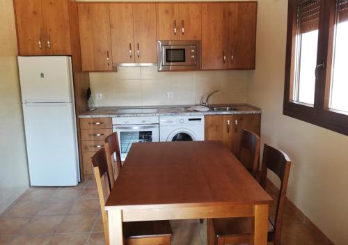 una cucina con tavolo in legno, sedie e frigorifero di Torrehermosa Rural a Torrehermosa