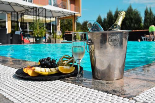 a plate of fruit and a glass of wine next to a pool at Garni hotel Mali predah - novi deo in Knjazevac.
